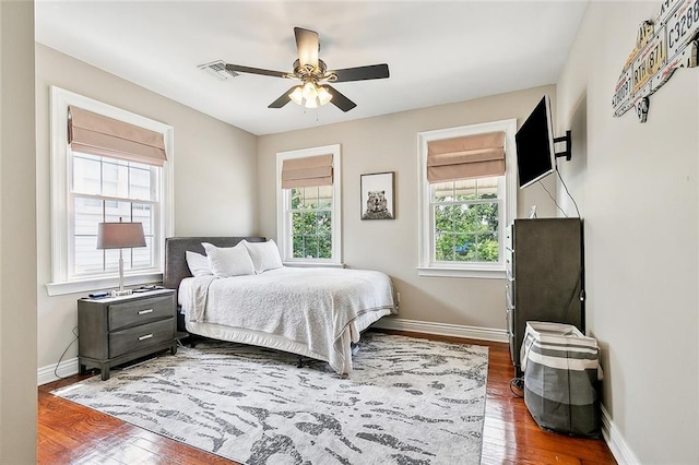 bedroom with dark hardwood / wood-style flooring, multiple windows, and ceiling fan