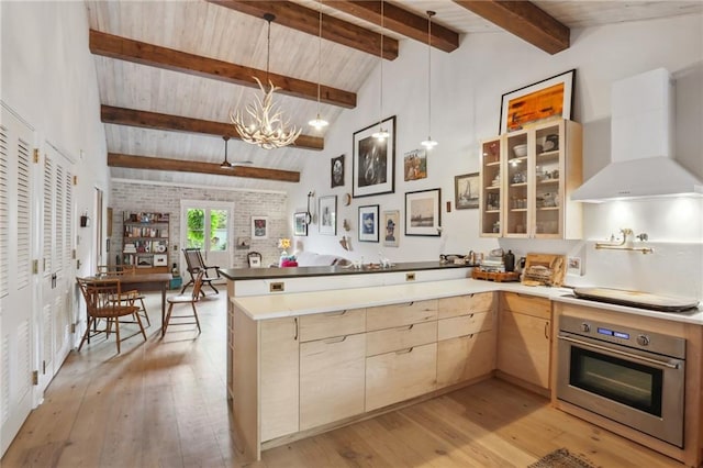 kitchen with kitchen peninsula, light hardwood / wood-style floors, oven, and range hood