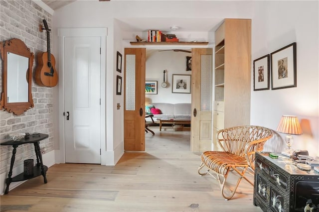 hallway with light hardwood / wood-style floors and brick wall