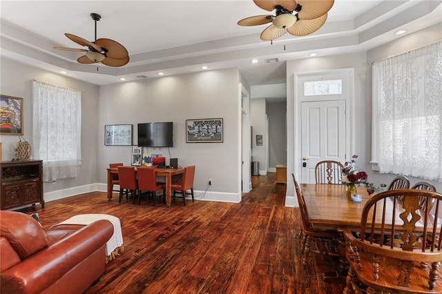 dining space featuring a tray ceiling, ceiling fan, and dark wood-type flooring