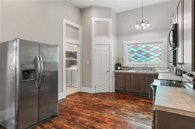 kitchen with appliances with stainless steel finishes, dark wood-type flooring, sink, decorative light fixtures, and a chandelier