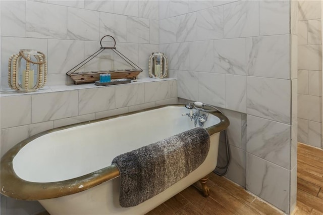 bathroom with a tub to relax in, tile walls, and hardwood / wood-style flooring