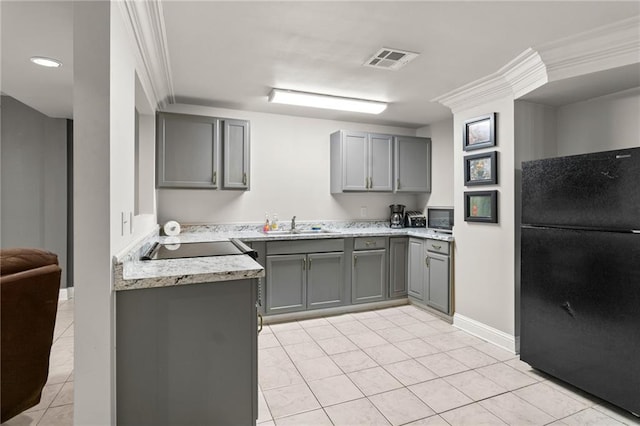 kitchen featuring light tile patterned floors, gray cabinetry, black fridge, and ornamental molding