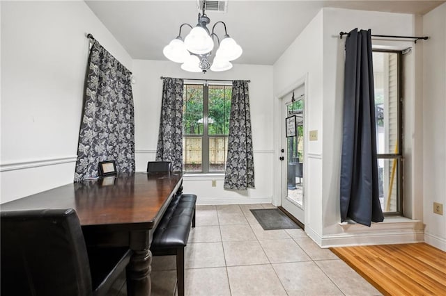 dining space with light hardwood / wood-style flooring and a chandelier