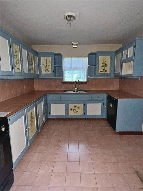 kitchen with blue cabinetry, dishwasher, sink, and light tile patterned floors