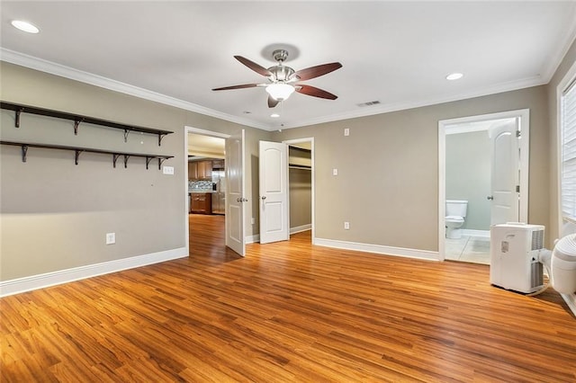 unfurnished bedroom featuring a spacious closet, ornamental molding, ensuite bathroom, ceiling fan, and light hardwood / wood-style flooring