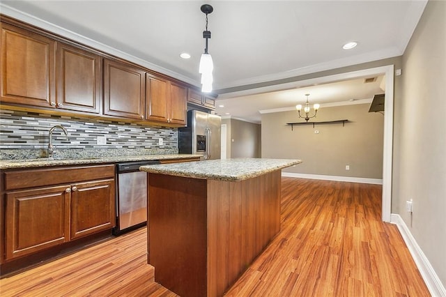 kitchen featuring light wood-type flooring, decorative backsplash, a kitchen island, and appliances with stainless steel finishes