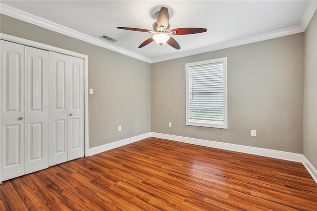 unfurnished bedroom with a closet, wood-type flooring, ceiling fan, and crown molding