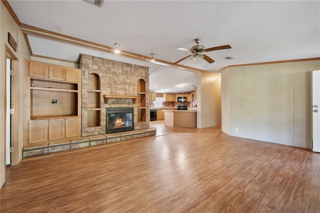 unfurnished living room with ceiling fan, a fireplace, light hardwood / wood-style floors, and a textured ceiling