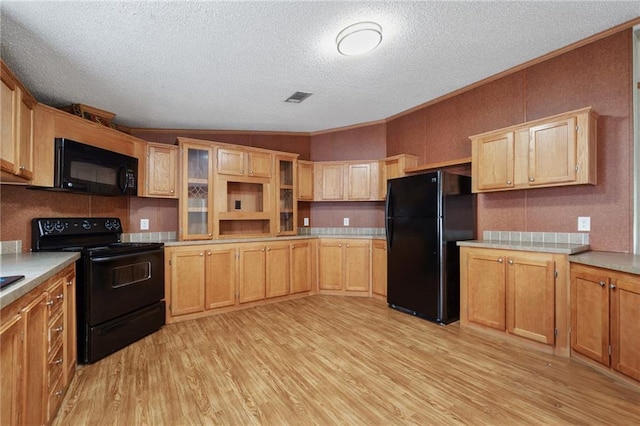 kitchen featuring light hardwood / wood-style flooring, crown molding, a textured ceiling, vaulted ceiling, and black appliances