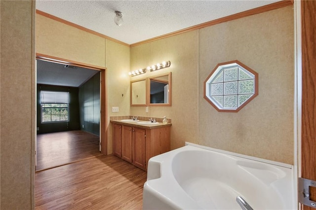 bathroom with hardwood / wood-style floors, vanity, a tub, and a textured ceiling