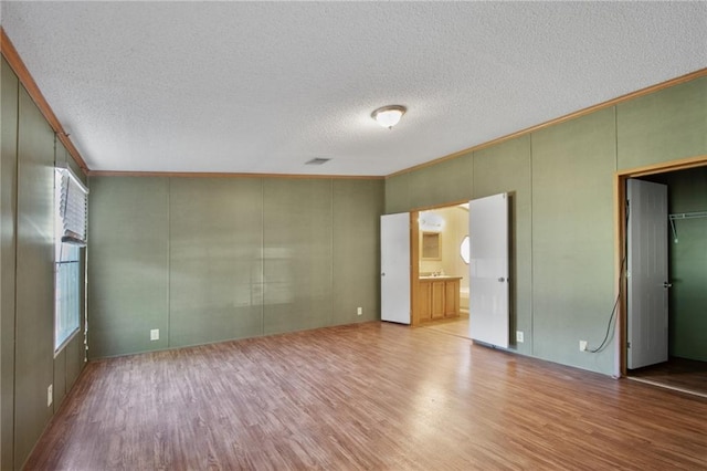 spare room featuring light wood-type flooring and crown molding