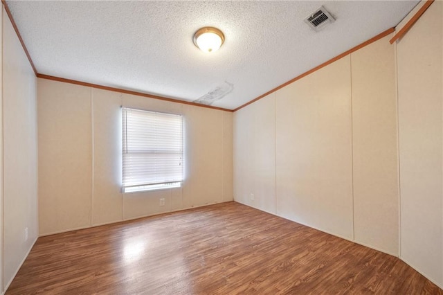 spare room with wood-type flooring, a textured ceiling, and ornamental molding