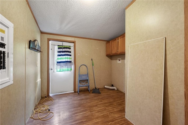 washroom featuring a textured ceiling, light hardwood / wood-style floors, cabinets, and crown molding