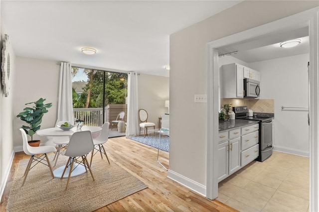 kitchen with backsplash, white cabinetry, light wood-type flooring, and appliances with stainless steel finishes