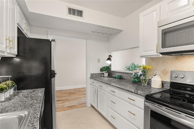 kitchen featuring decorative backsplash, stone countertops, white cabinetry, light wood-type flooring, and appliances with stainless steel finishes