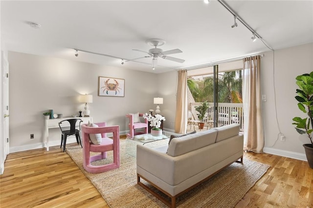 living room featuring light wood-type flooring, rail lighting, and ceiling fan