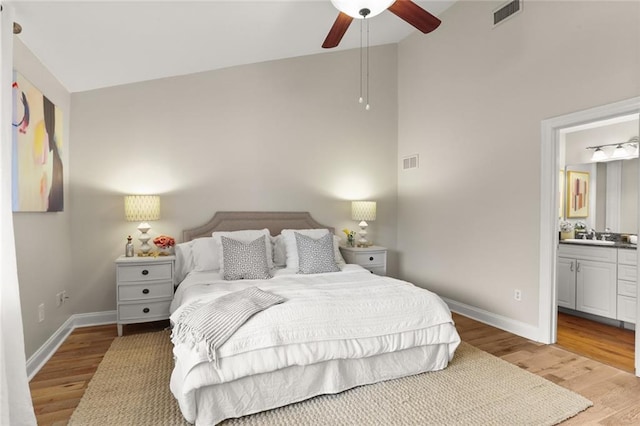 bedroom featuring connected bathroom, ceiling fan, high vaulted ceiling, and light hardwood / wood-style floors