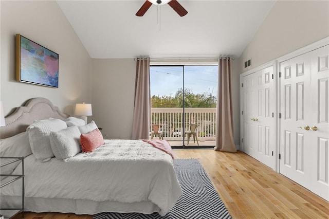 bedroom with access to exterior, hardwood / wood-style floors, vaulted ceiling, two closets, and ceiling fan