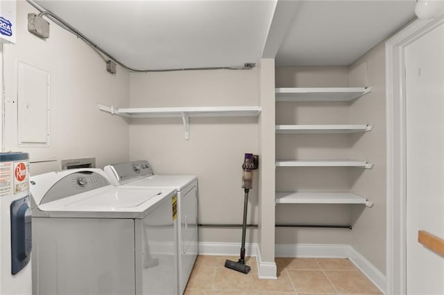 clothes washing area featuring electric panel, washer and dryer, light tile patterned floors, and electric water heater