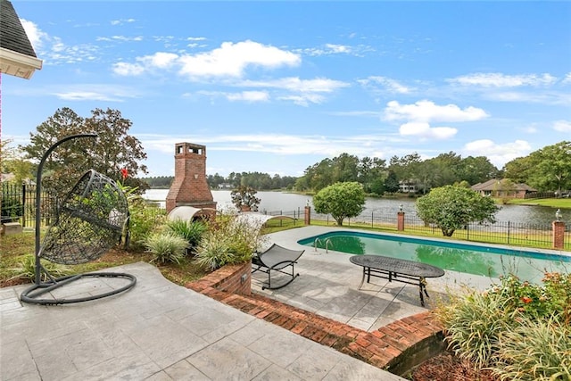 view of pool with a patio, a water view, and an outdoor brick fireplace