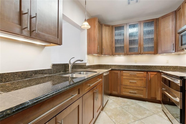 kitchen with stainless steel appliances, light tile patterned floors, sink, and decorative light fixtures