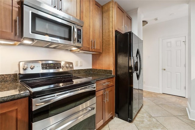 kitchen with dark stone counters, light tile patterned flooring, and stainless steel appliances