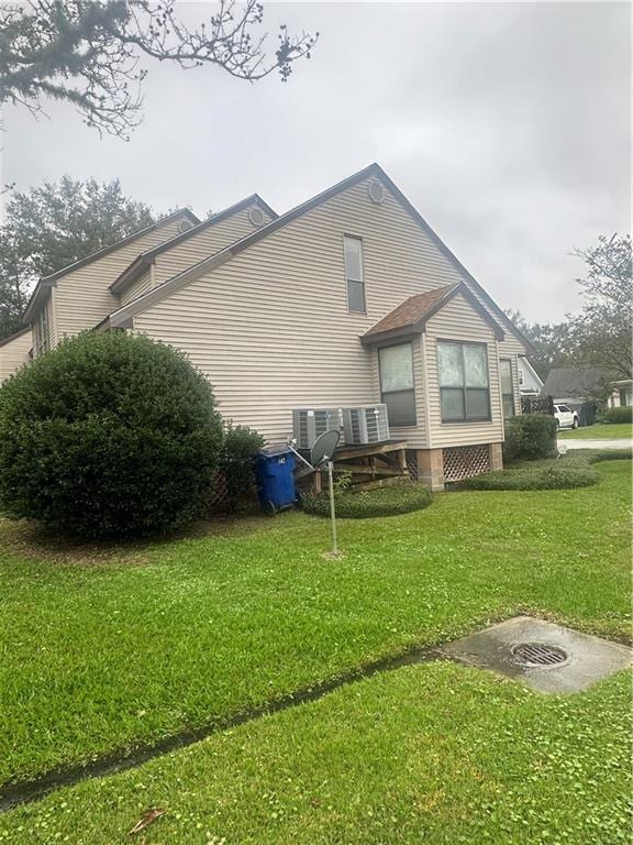 view of property exterior featuring central AC unit and a lawn