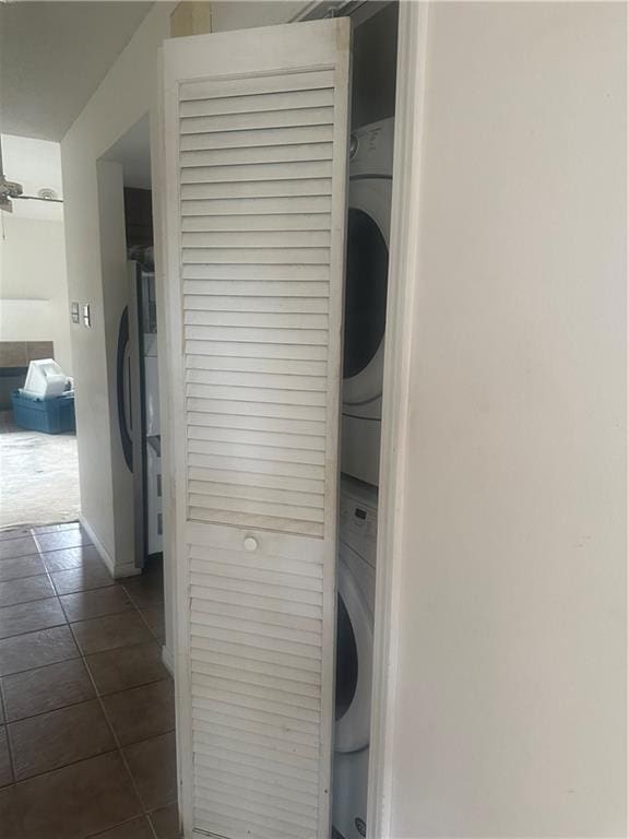 laundry area with dark tile patterned floors and stacked washer and clothes dryer