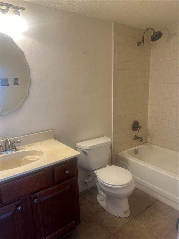 full bathroom featuring tile patterned flooring, tiled shower / bath, a textured ceiling, vanity, and toilet