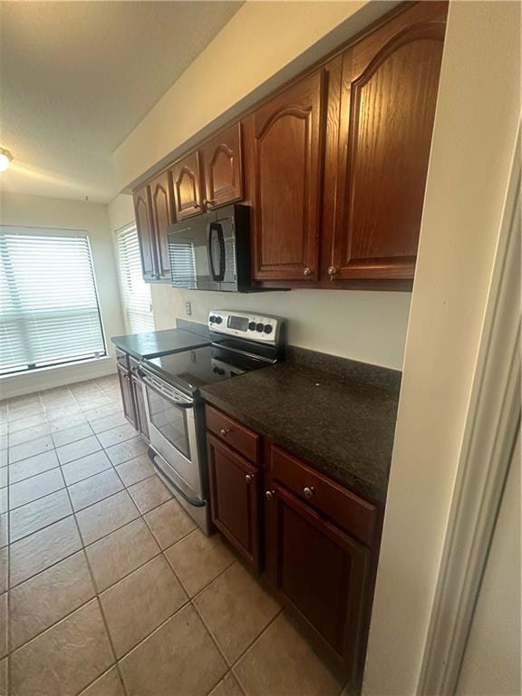 kitchen with dark stone countertops, electric stove, and light tile patterned flooring