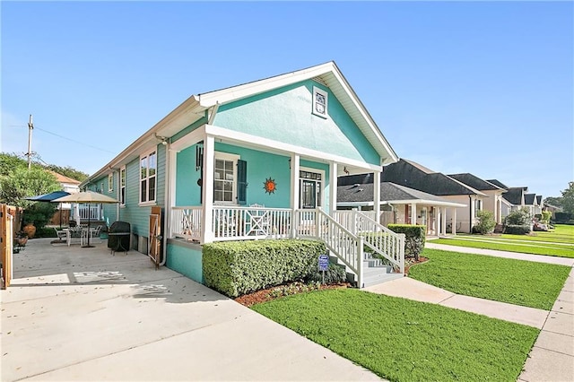 view of front of house with a porch, a front lawn, and a patio area