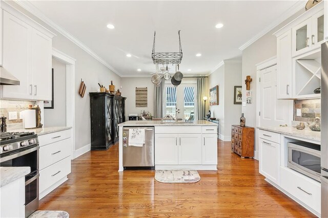 kitchen with white cabinetry, appliances with stainless steel finishes, light hardwood / wood-style floors, and a kitchen island