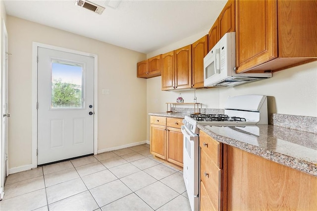 kitchen with white appliances, light tile patterned floors, and light stone counters