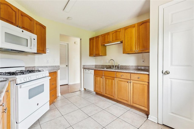 kitchen with light tile patterned floors, white appliances, and sink