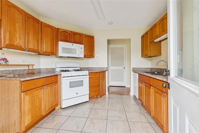 kitchen with white appliances, sink, light stone counters, and light tile patterned flooring