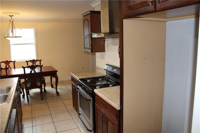 kitchen featuring ornamental molding, light tile patterned floors, range with gas stovetop, hanging light fixtures, and wall chimney exhaust hood