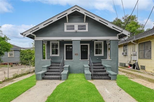 bungalow with cooling unit, covered porch, and a front yard