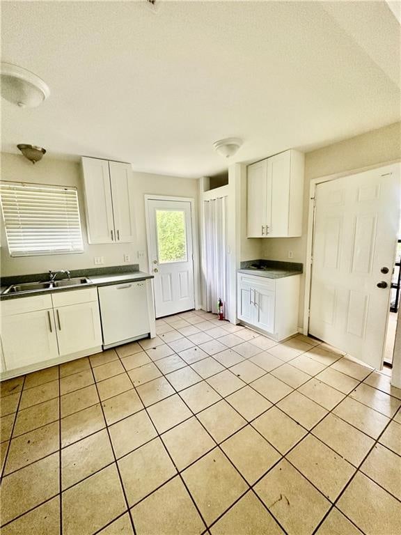 kitchen featuring dishwasher, a textured ceiling, sink, light tile patterned flooring, and white cabinetry