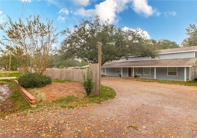 view of front facade featuring fence, driveway, and a porch