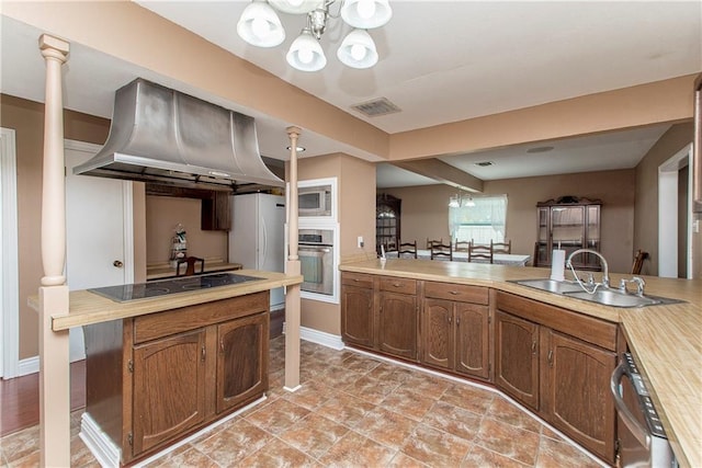 kitchen featuring extractor fan, stainless steel appliances, a chandelier, a sink, and light countertops