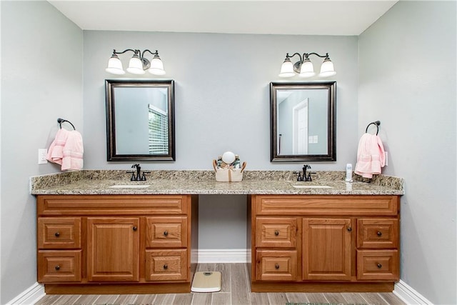 full bath featuring double vanity, baseboards, and wood finished floors
