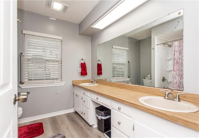 bathroom featuring toilet, wood finished floors, double vanity, and a shower with shower curtain