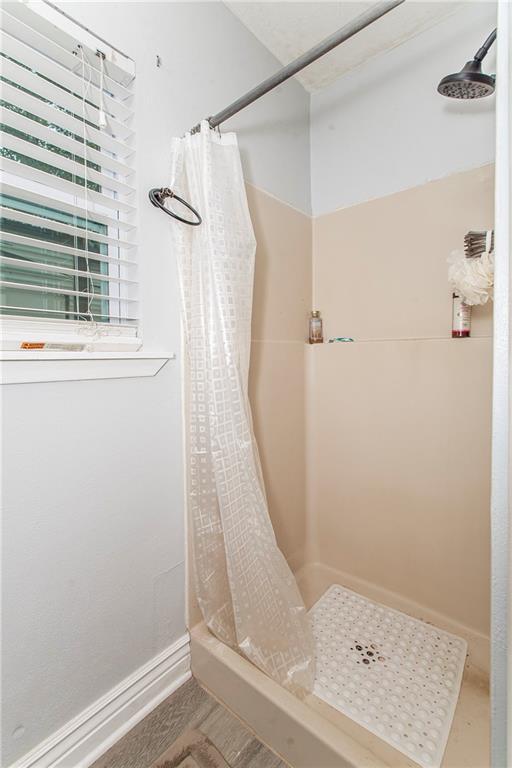 full bath featuring a stall shower and baseboards