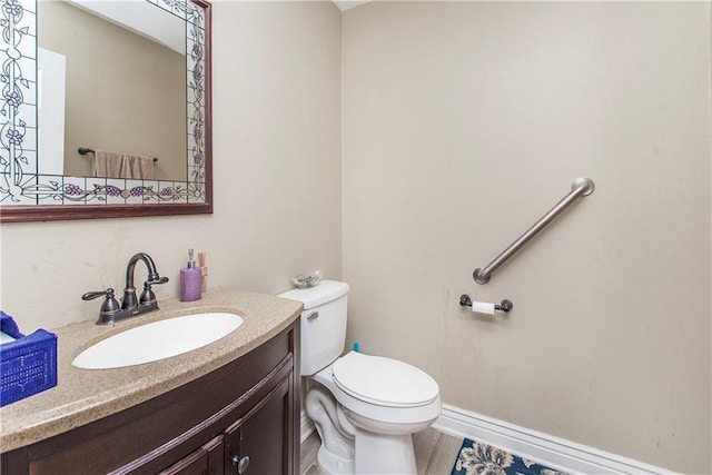 bathroom featuring toilet, vanity, and wood finished floors