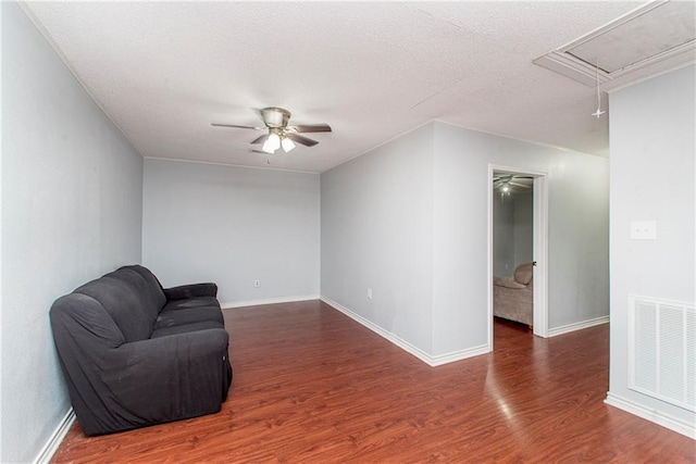 unfurnished room featuring attic access, ceiling fan, wood finished floors, baseboards, and a textured ceiling