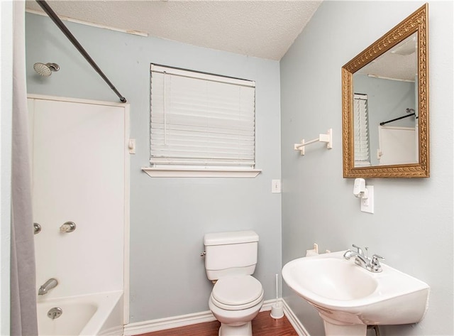 bathroom with a textured ceiling, toilet, shower / bath combination, a sink, and baseboards