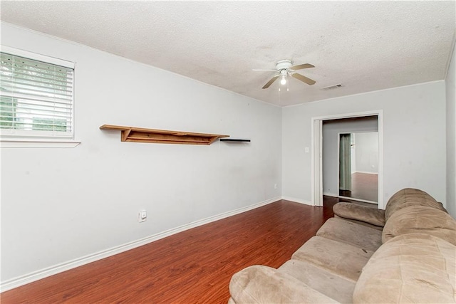 living area with wood finished floors, a textured ceiling, ceiling fan, and baseboards