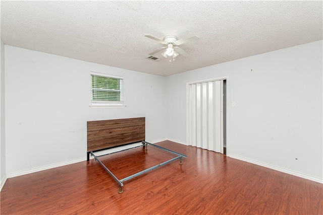 unfurnished bedroom featuring wood finished floors, a textured ceiling, baseboards, and ceiling fan