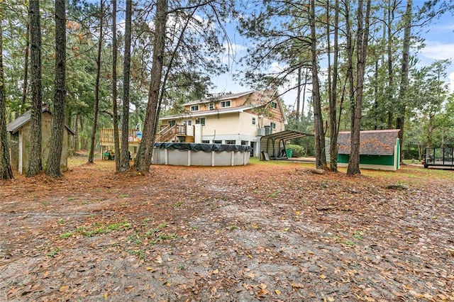 view of yard featuring a swimming pool side deck, a carport, and a storage shed